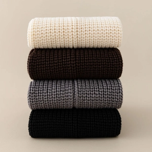 Close-up of ribbed knit leg warmers in cream brown grey and black stacked layers