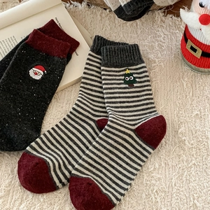 Détail de chaussettes de Noël en laine avec broderie Père Noël sur tapis en peluche blanc