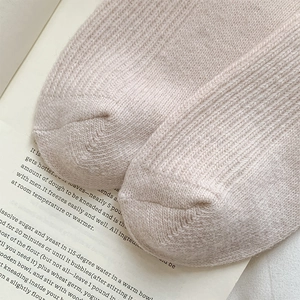 Macro detail of the fine ribbed knit texture on soft pink wool socks for women