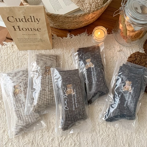 Close-up of five pairs of warm knit teddy bear embroidered socks in various brown tones