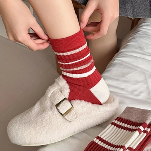 Close-up of red and white striped knit socks paired with fuzzy cream buckled mules