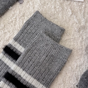 Dettaglio di calze in lana a maglia con texture grigia e motivo a righe bianche e nere