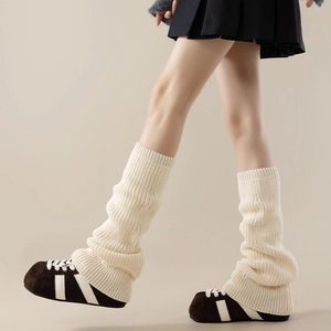 Detail of cream rib-knit leg warmers showing thick texture and slouchy style above sneakers