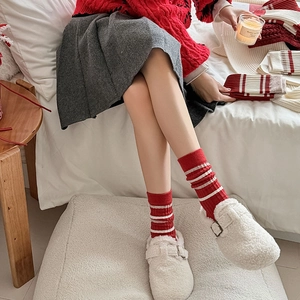 Detail of red and white striped knit mid-calf socks with fuzzy buckle slippers