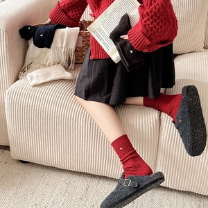 Detail of red wool socks with sheep embroidery and gray felt buckle mule shoes