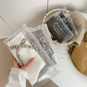 Detail of knitted mid-calf socks with leopard print bow ribbons in luxury packaging
