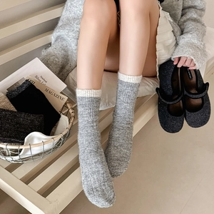 Thick wool knit socks for women in grey and beige color block on a wooden bench