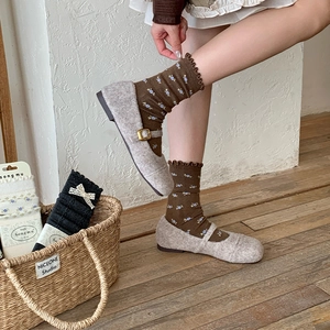 Detail of dark brown floral crew socks with ruffle edges and gray Mary Jane shoes