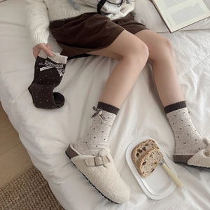 Close-up of wool socks with bow tie and polka dot pattern worn with plush slippers