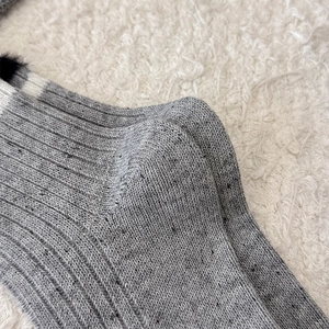 Dettaglio calzini in maglia a coste grigie con riga bianca e bordo in peluche nero