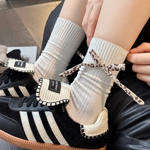 Detail of white ribbed crew socks featuring leopard print bow ties on the side