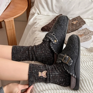 Detail of warm brown knit socks with bear embroidery paired with grey wool felt mules