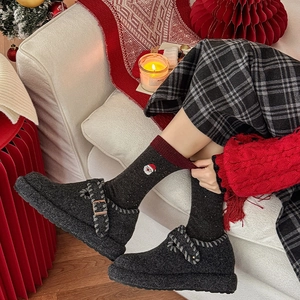 Détail de chaussettes en laine avec broderie Père Noël et mules grises en décor de Noël