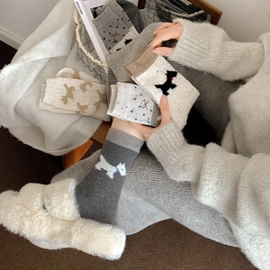 Nahaufnahme von warmen Fair-Isle-Stricksocken mit süßem Hundemuster und Schleife