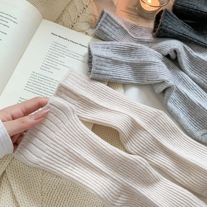 Close-up of thick ribbed wool socks in neutral tones on a cozy knit blanket background