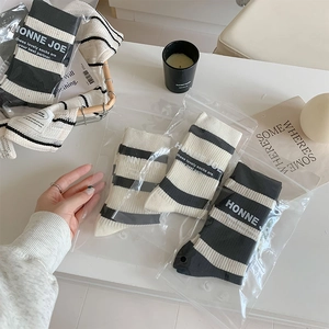 Detailed view of three pairs of black and white striped cotton socks in clear polybags