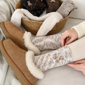 Detailed view of plush brown slippers and knit socks with cute bear embroidery detail