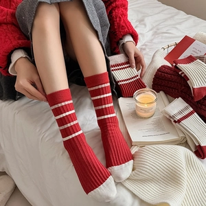 Red and white striped mid-calf knit socks for women in a cozy festive holiday setting