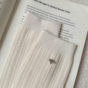 Macro shot of white ribbed knit socks featuring a silver pony metal accessory detail