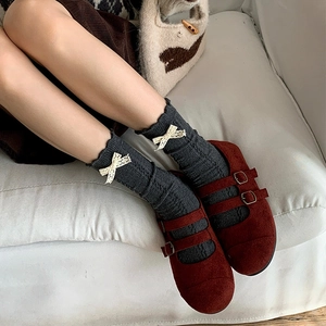 Close-up of Mary Jane shoes with grey knit socks featuring a white lace bow detail