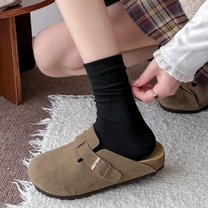 Detail of tan suede Boston clogs with adjustable buckle and cork footbed worn with socks