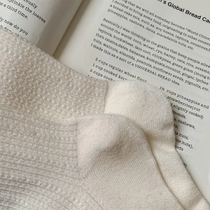 Close-up of off-white knitted wool socks with ribbed texture over a vintage book