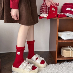 Gros plan de chaussettes festives rouges brodées et de pantoufles en fausse fourrure blanche
