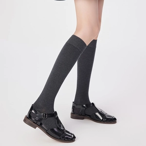 Detail of dark grey vertical striped wool socks paired with black leather sandals