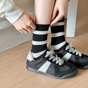 Classic black and white striped crew socks paired with black sneakers on wooden floor