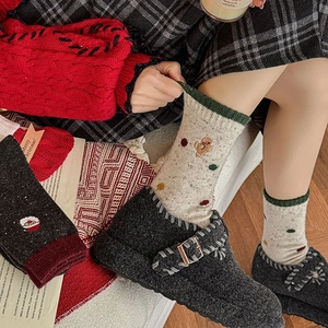 Chaussettes de Noël en laine avec broderies et chaussons dans un décor de fête hivernal
