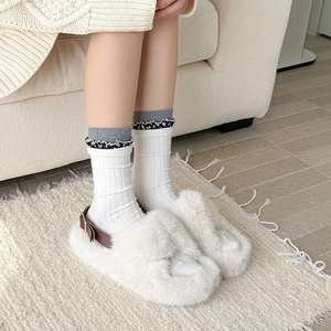 Dettaglio calze in lana vintage abbinate a pantofole color crema e cinturino in pelle