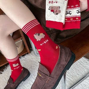 Détail de chaussettes rouges avec motif de cheval animé et lingots dorés