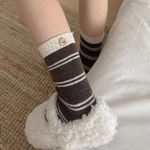 Close-up of wool socks with brown stripes and a cute smiley face wooden button detail