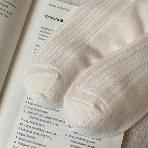 Close-up of cream knit socks with waffle texture resting on vintage book pages