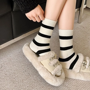 Detail of black and white striped cotton socks paired with beige plush platform sandals