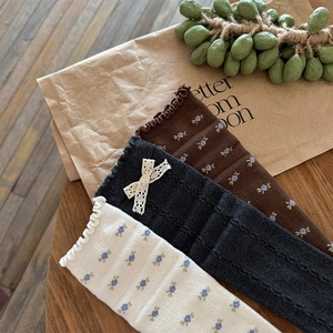 Detailed close-up of floral wool socks and black cable knit socks with lace bows