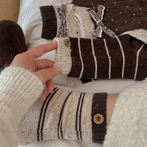 Detail of wool knit leg warmers with wood buttons, lace trim and floral bow accents