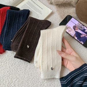 Close-up of ribbed wool socks featuring metallic H accents in red, navy and cream