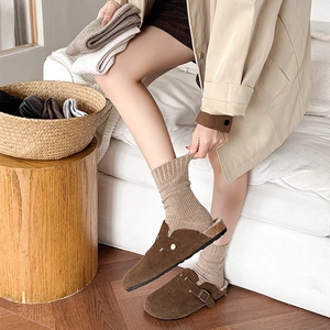 Close-up of brown suede clogs with plush fleece lining and khaki ribbed wool socks