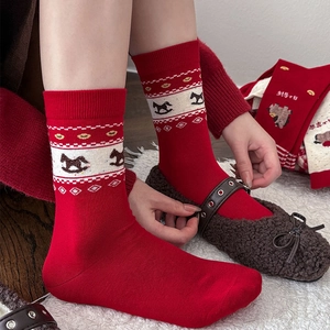 Détail de chaussettes rouges avec jacquard cheval à bascule blanc et motifs festifs