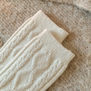 Detailed macro of cream cable knit wool socks featuring classic ribbed texture and warm fabric