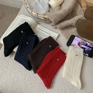 Detailed close-up of wool mid-tube socks set with metallic puppy charms in five colors