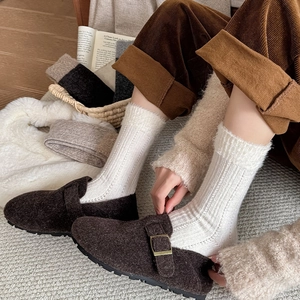 Detail of plush fuzzy trimmed white rib knit socks worn with brown suede mule slippers
