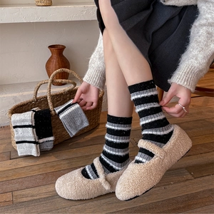 Dettaglio di calze di lana a righe con scarpe Mary Jane in pile su sfondo di legno caldo