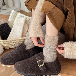 Detail of warm wool socks paired with brown felt clogs and corduroy pants in a cozy setting