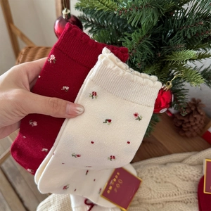 Detailed close-up of floral embroidery and ruffled cuffs on festive knit wool socks
