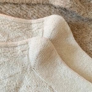 Detailed close-up of warm white knitted fabric with intricate jacquard texture on wool socks