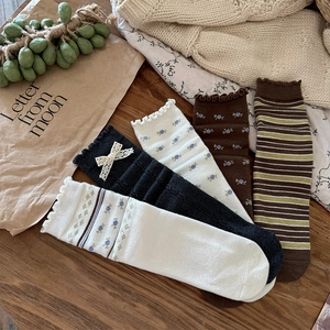 Detailed knit texture of wool mid-calf socks with floral embroidery and lace bows