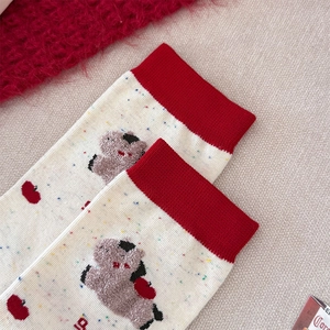 Détail de chaussette crème mouchetée avec revers rouge et broderie animale en peluche
