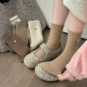 Detailed texture of thick wool socks with ribbed knit and small metal charm detail